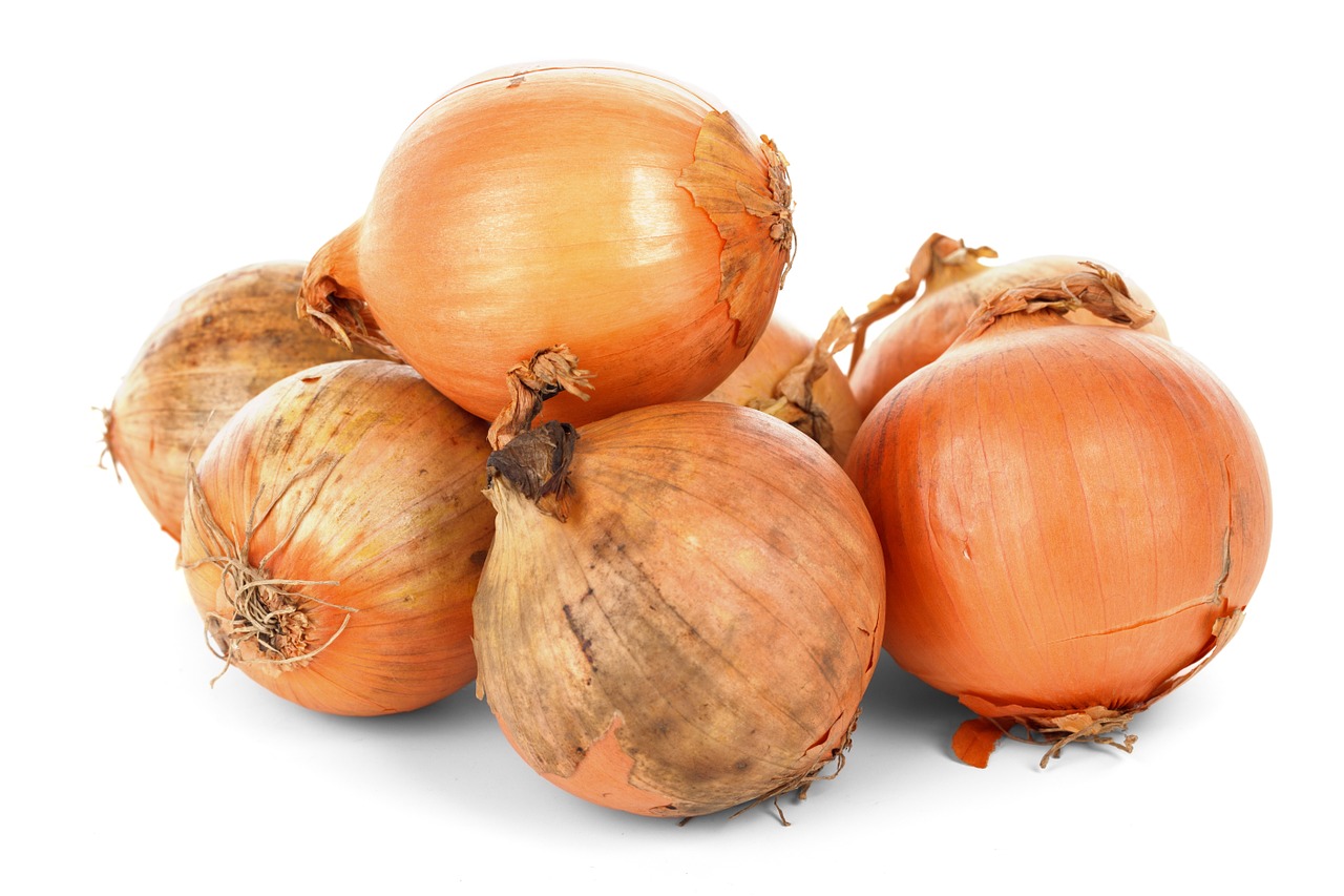 A pile of whole yellow onions on a white background, symbolizing Mullvad VPN's new onion service for the Tor network.